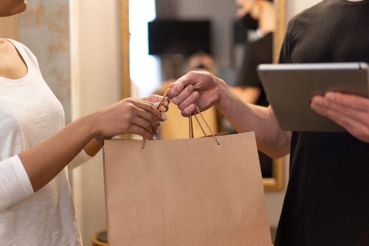 Shopping bag handed across a store counter